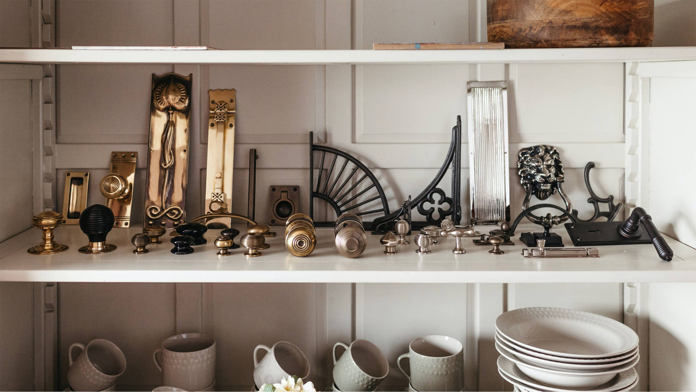 A selection of brass, nickel and iron hardware pieces on a dresser shelf