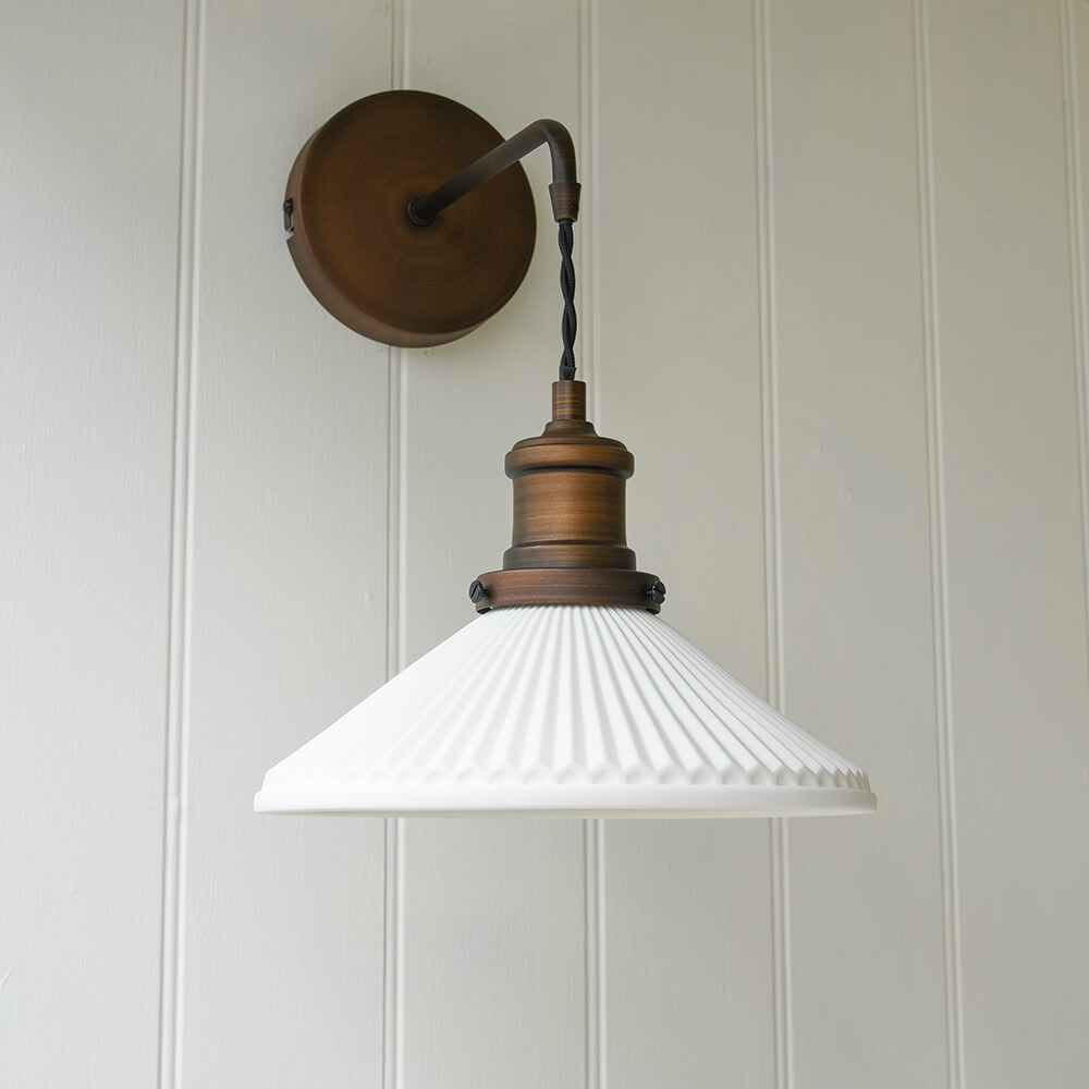 Bronze coloured wall light with white fluted ceramic shade suspended on twisted fabric cable