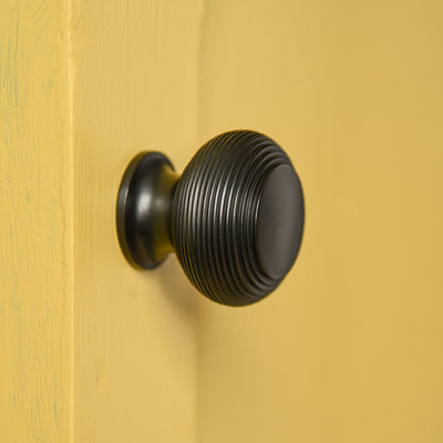 BLACK BEEHIVE STYLE CABINET KNOB ON YELLOW CUPBOARD