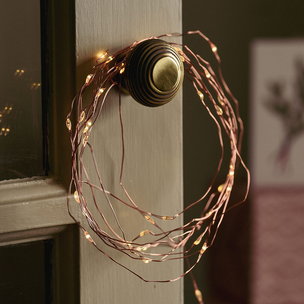 Hoop of copper wire lights hung on a cupboard door