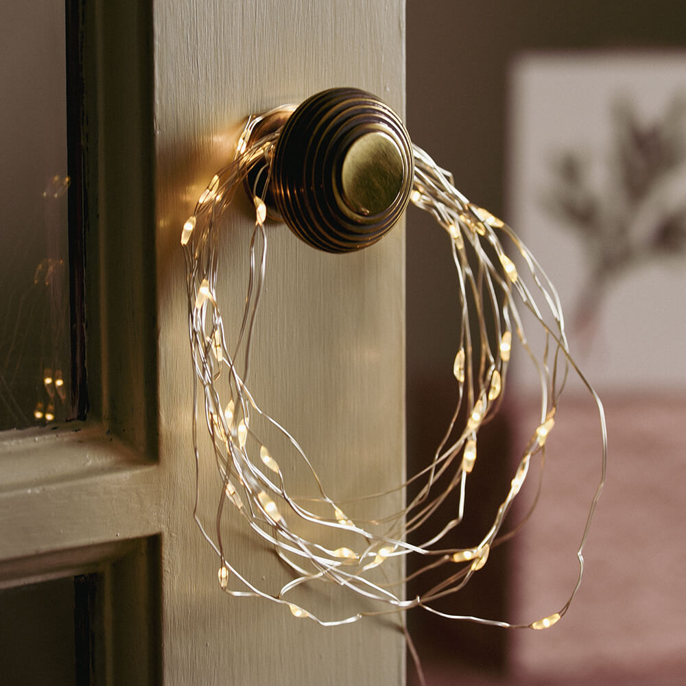 Hoop of silver wire lights hung on a cupboard door