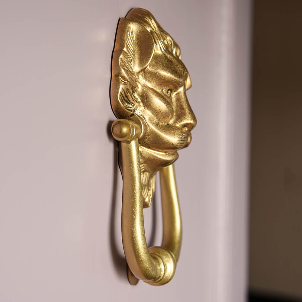 Gold lion head door knocker profile on a lilac painted door