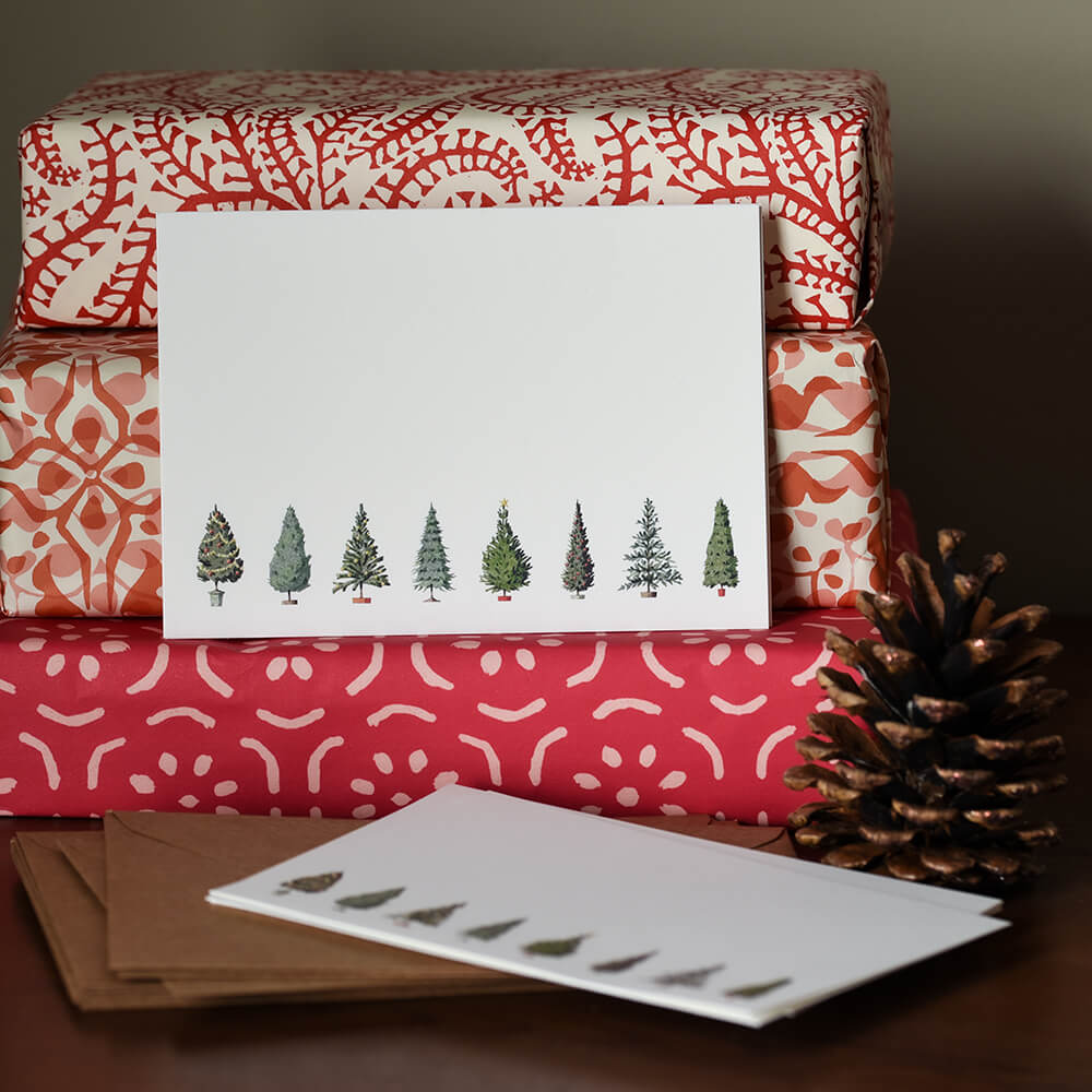 12 cards featuring a row of christmas trees shown on a pile of parcels