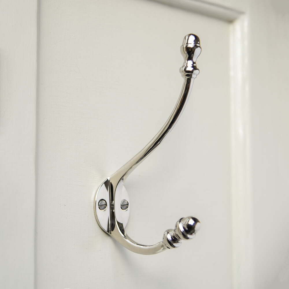 Silver double coat hook with curved arms and finials in the shape of acorns