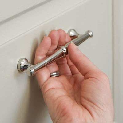 Elongated nickel plated drawer pull in a decorative Regency style held in hand to show proportions