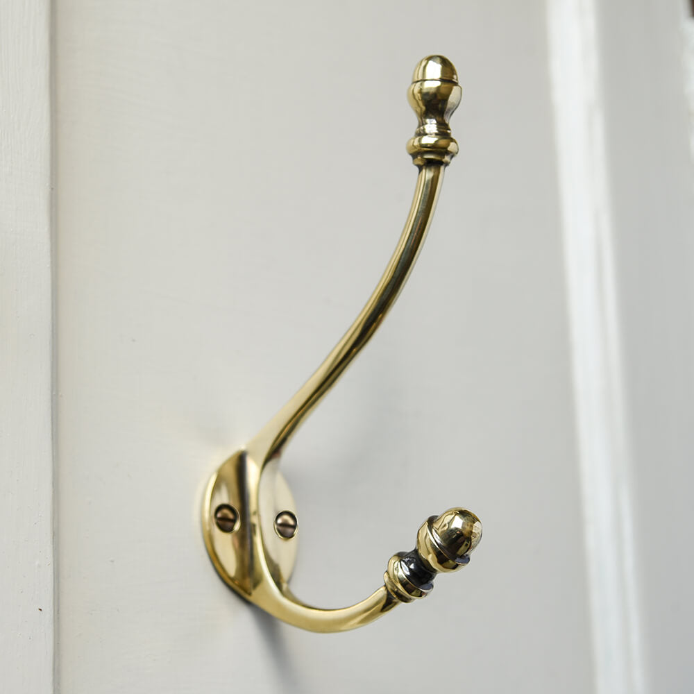 Brass double coat hook with acorn shaped finials