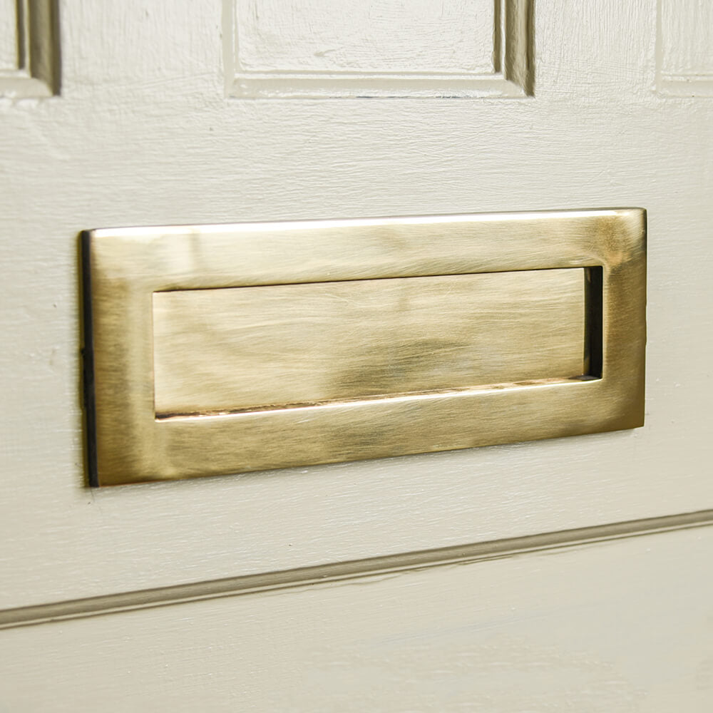 Aged brass letterbox on a cream door