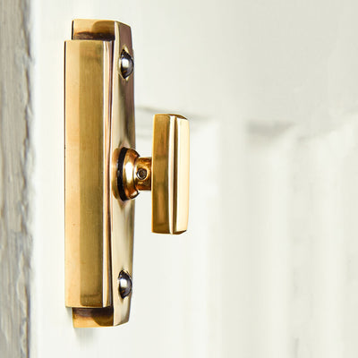 Art deco style thumbturn on a door shown in profile