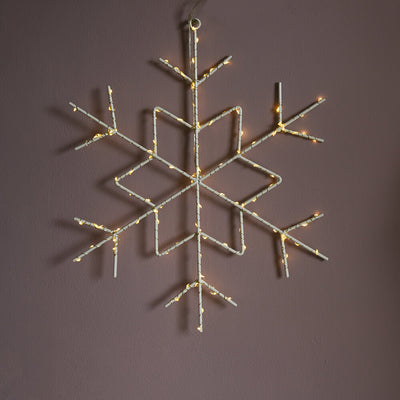 Snowflake light seen illuminated on a dark wall