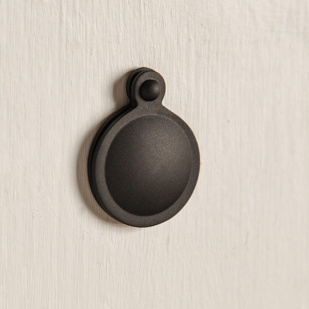 Round black escutcheon fixed to a neutral door.