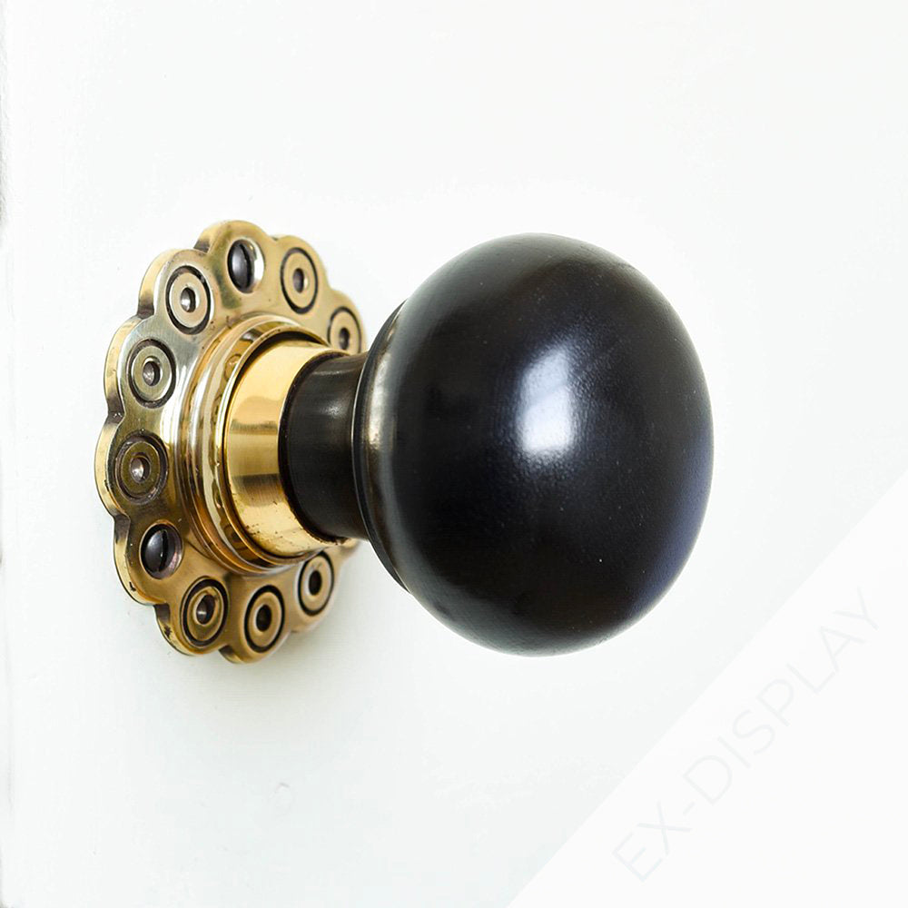 Solid ebony bun door knobs with brass petal backplate on a white background with a watermark and ex display text in the corner